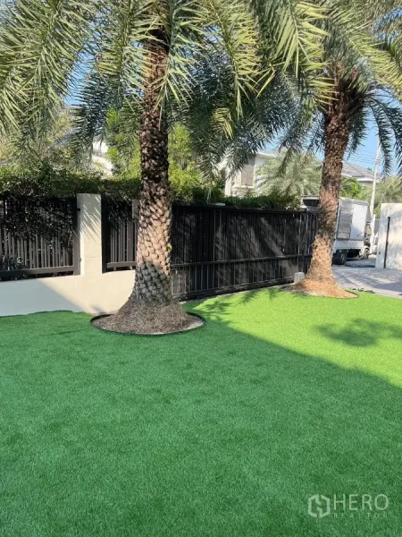 Detached House for rent in Bang Phli, Samut Prakan - Front garden with palm trees and synthetic grass beside a black gate