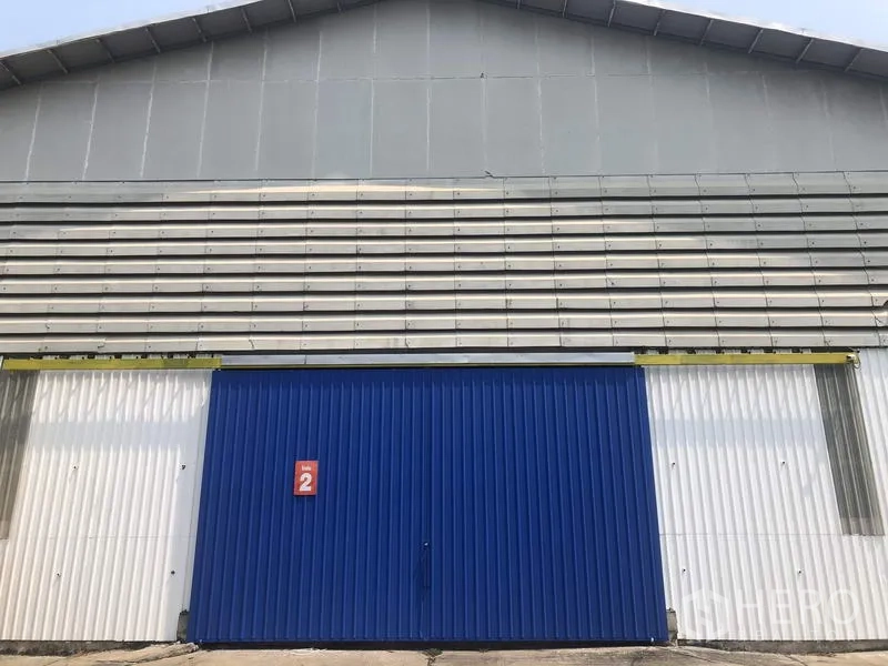 Warehouse for rent in Pak Kret, Nonthaburi - Front view of the warehouse facade with a wide blue sliding door and corrugated metal panels