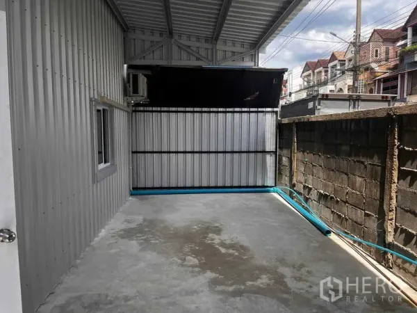 Warehouse for rent in Lat Phrao, Bangkok - Covered side yard with concrete floor and metal fencing at the rear of the warehouse, suitable for loading or utility area.