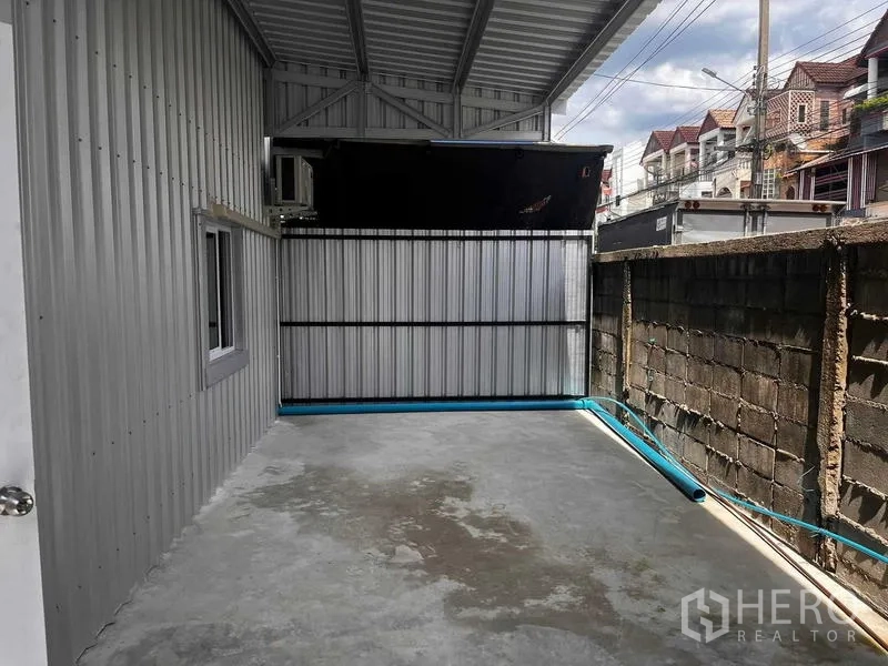 Warehouse for rent in Lat Phrao, Bangkok - Covered side yard with concrete floor and metal fencing at the rear of the warehouse, suitable for loading or utility area.