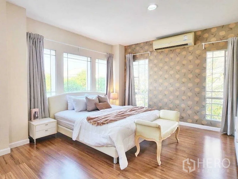 Detached House for rent in Prawet, Bangkok - Master bedroom angle showing feature wall, bench and wide windows bringing in natural light.