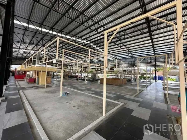 Warehouse for rent in Sai Noi, Nonthaburi - Interior of the warehouse with high truss roof and modular frames for stalls or offices.
