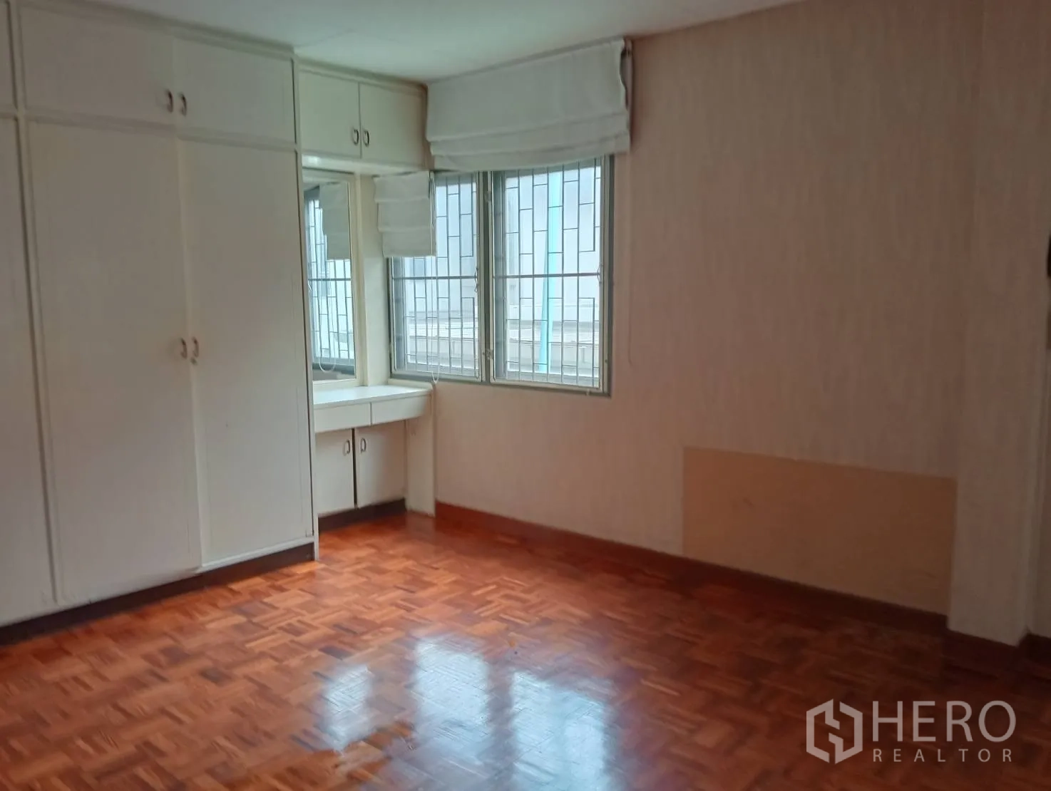 Home Office for rent in Khlong Toei, Bangkok - Corner bedroom with built-in white wardrobes, dressing table and barred windows.