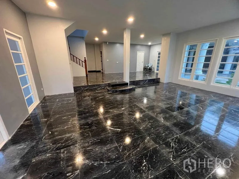 Detached House for sale in Bang Na, Bangkok - Open-plan hall with black marble floors, columns, staircase and abundant windows.