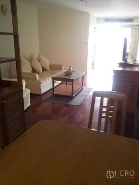 Condominium for rent - Living area with cream sofa, coffee table and TV on polished wooden flooring.