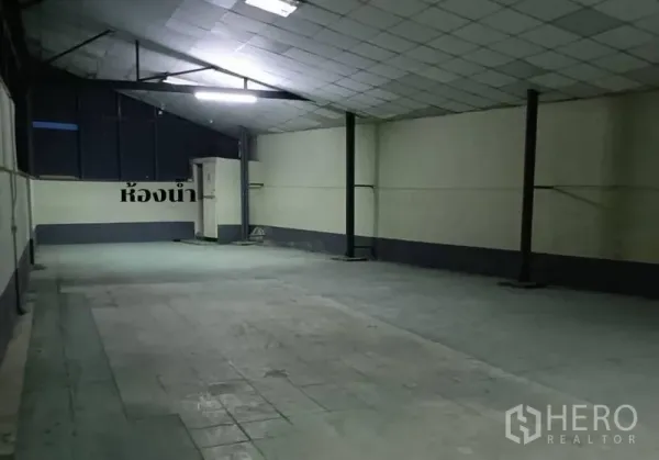 Warehouse for rent in Bang Khen, Bangkok - Enclosed warehouse room with tiled ceiling, bright lighting and restroom corner.