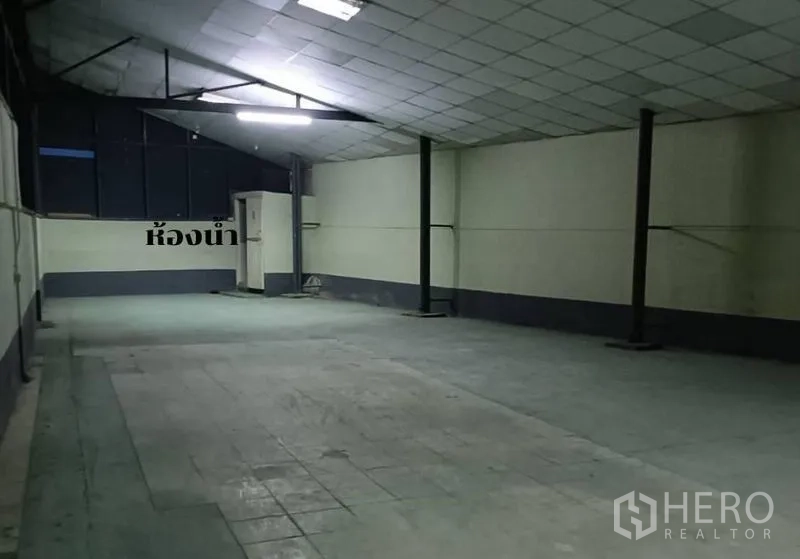 Warehouse for rent in Bang Khen, Bangkok - Enclosed warehouse room with tiled ceiling, bright lighting and restroom corner.