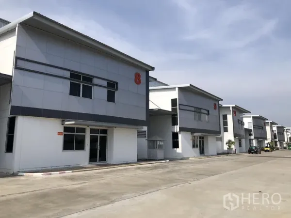 Factory for rent in Phra Nakhon Si Ayutthaya - Row of contemporary factory buildings along a wide internal road with parking.