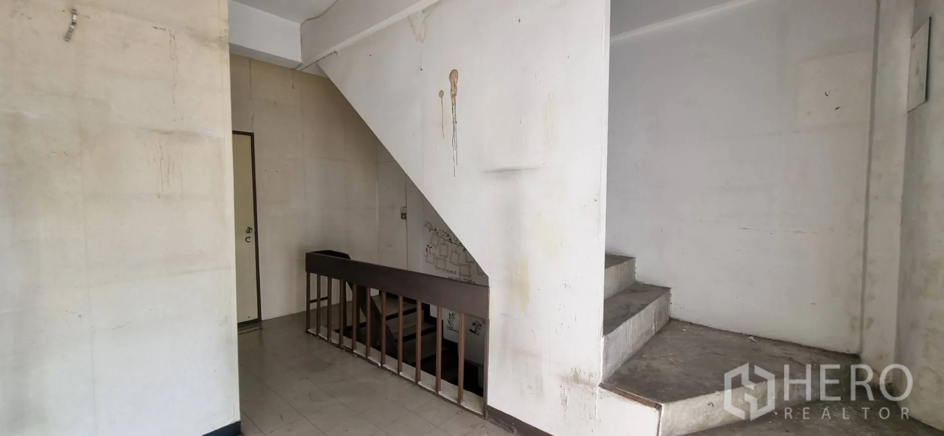 Shophouse for rent or sale in Bangkok - Stairwell area with concrete steps, railing and worn white walls.