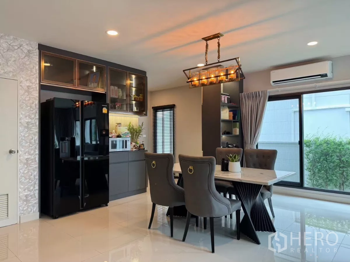 Detached House for rent in Bang Phli, Samut Prakan - Dining area with chandelier, marble-top table, built-in cabinets and black double-door fridge.