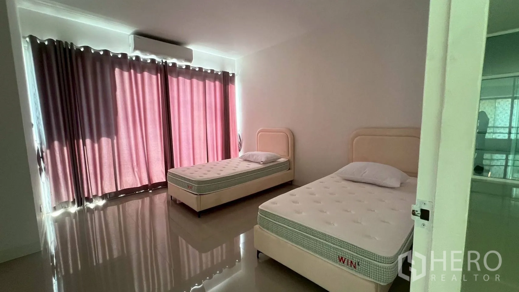 Home Office for rent in Wang Thonglang, Bangkok - Twin-bed room with pink blackout curtains and wall air conditioner.