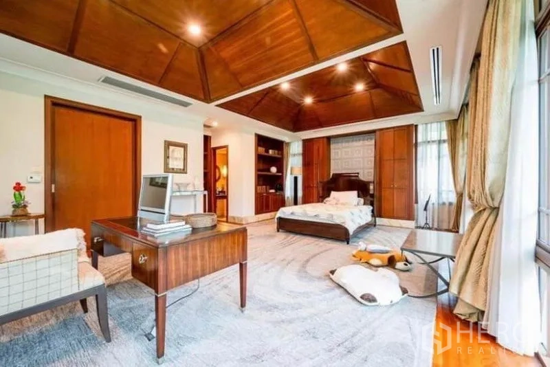 Detached House for rent in Khlong Toei, Bangkok - Large bedroom with wood-panel ceiling, desk, built-in shelving and expansive windows.