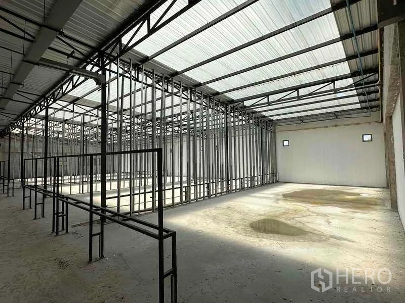 Warehouse for rent in Sai Noi, Nonthaburi - High-roof warehouse interior with steel trusses and framed bays, translucent panels bringing daylight.