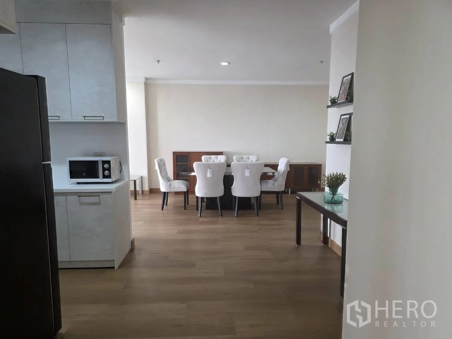 Condominium for rent in Khlong Toei, Bangkok - View from the kitchen toward the dining zone with white cabinetry and a microwave.