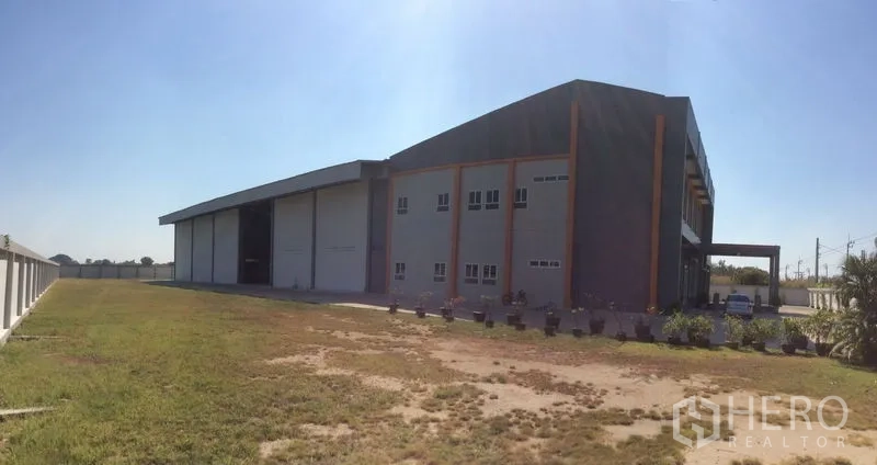 Factory for sale in Bang Sao Thong, Samut Prakan - Full side view across grassed setback and concrete driveway.