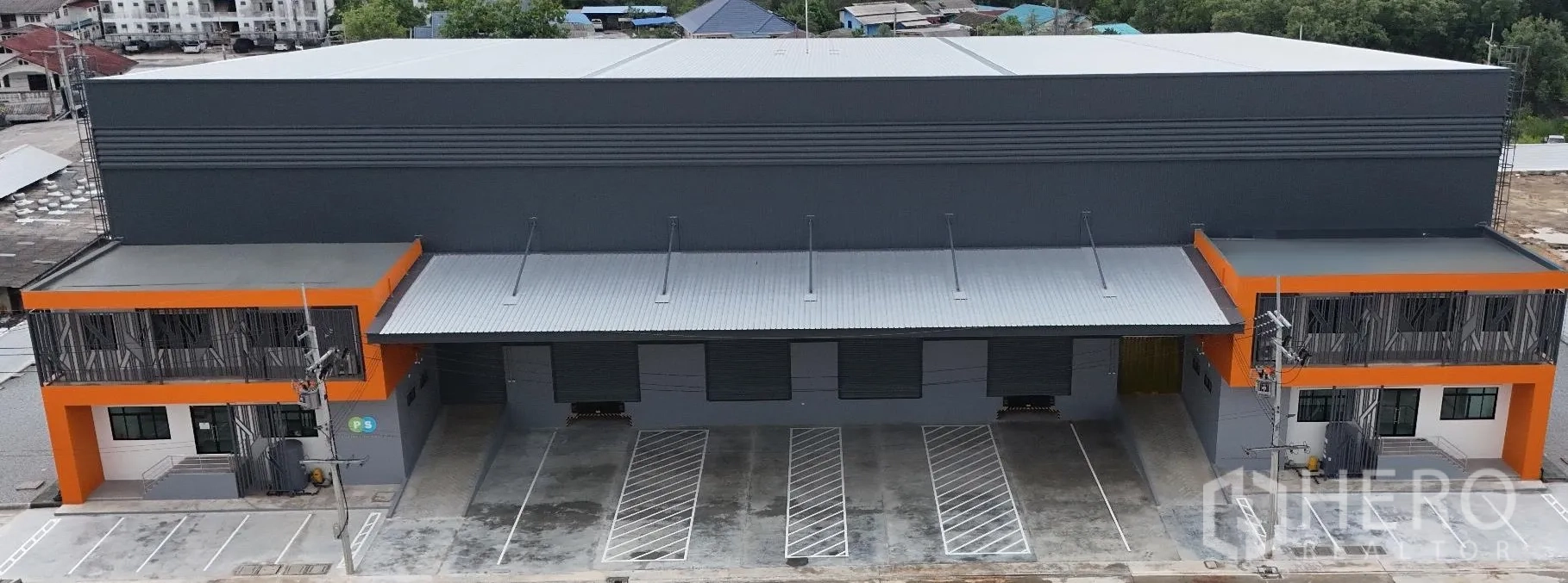 工厂 for rent in Bang Sao Thong, Samut Prakan - 现代化仓库外立面，带雨棚装卸区、卷闸门与划线停车位。