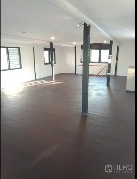 Detached House for rent in Khlong Toei, Bangkok - Spacious open-plan room with dark wooden flooring and multiple windows