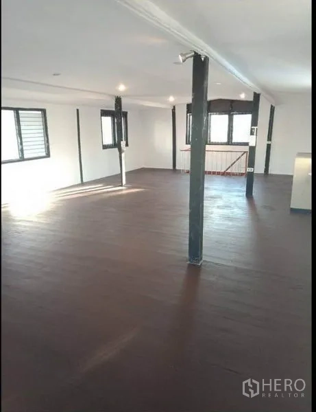 Detached House for rent in Khlong Toei, Bangkok - Spacious open-plan room with dark wooden flooring and multiple windows