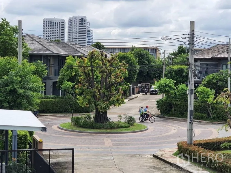 独立式住宅 出售在Suan Luang, Bangkok - 社区内绿化环岛，中央大树与周边低层住宅环境。