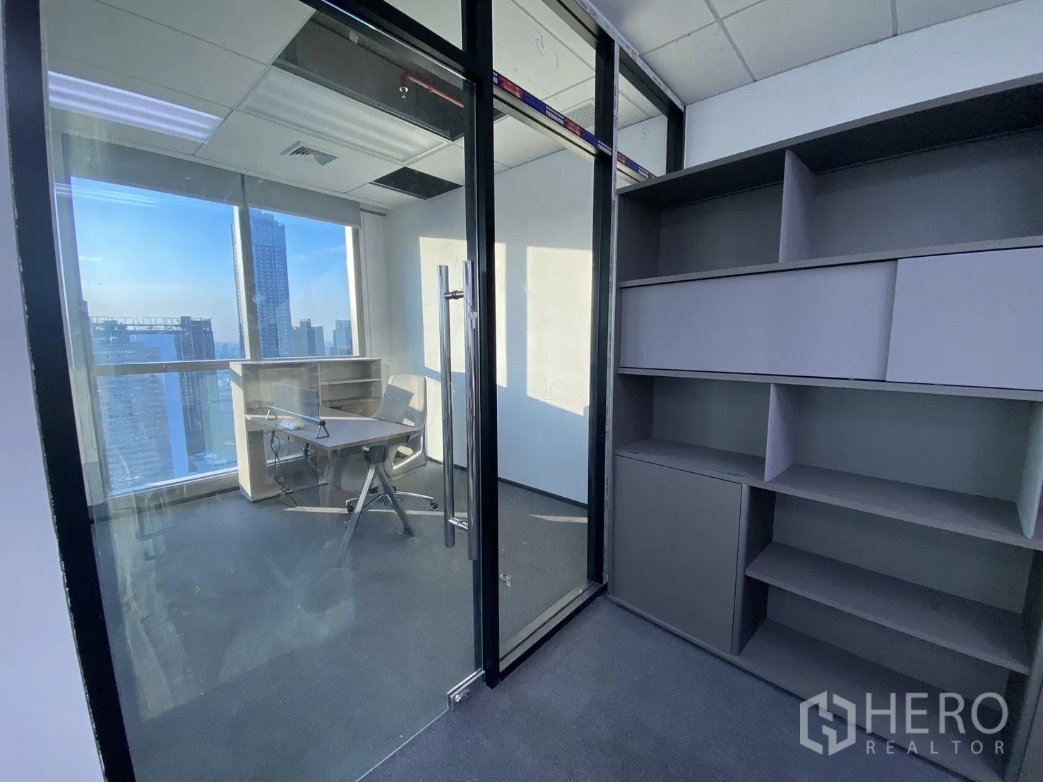 办公空间 for rent in Huai Khwang, Bangkok - 玻璃隔间的私密办公室，内有储物柜与书桌，落地窗享城市景观。