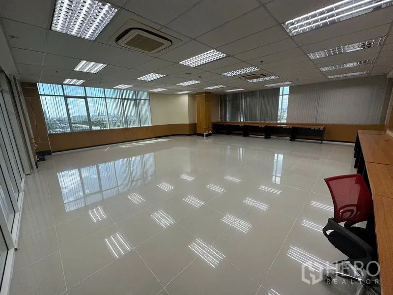 办公空间 出租在Suan Luang, Bangkok - 带大窗与百叶、内置长工作台和吊顶空调的办公室角落。