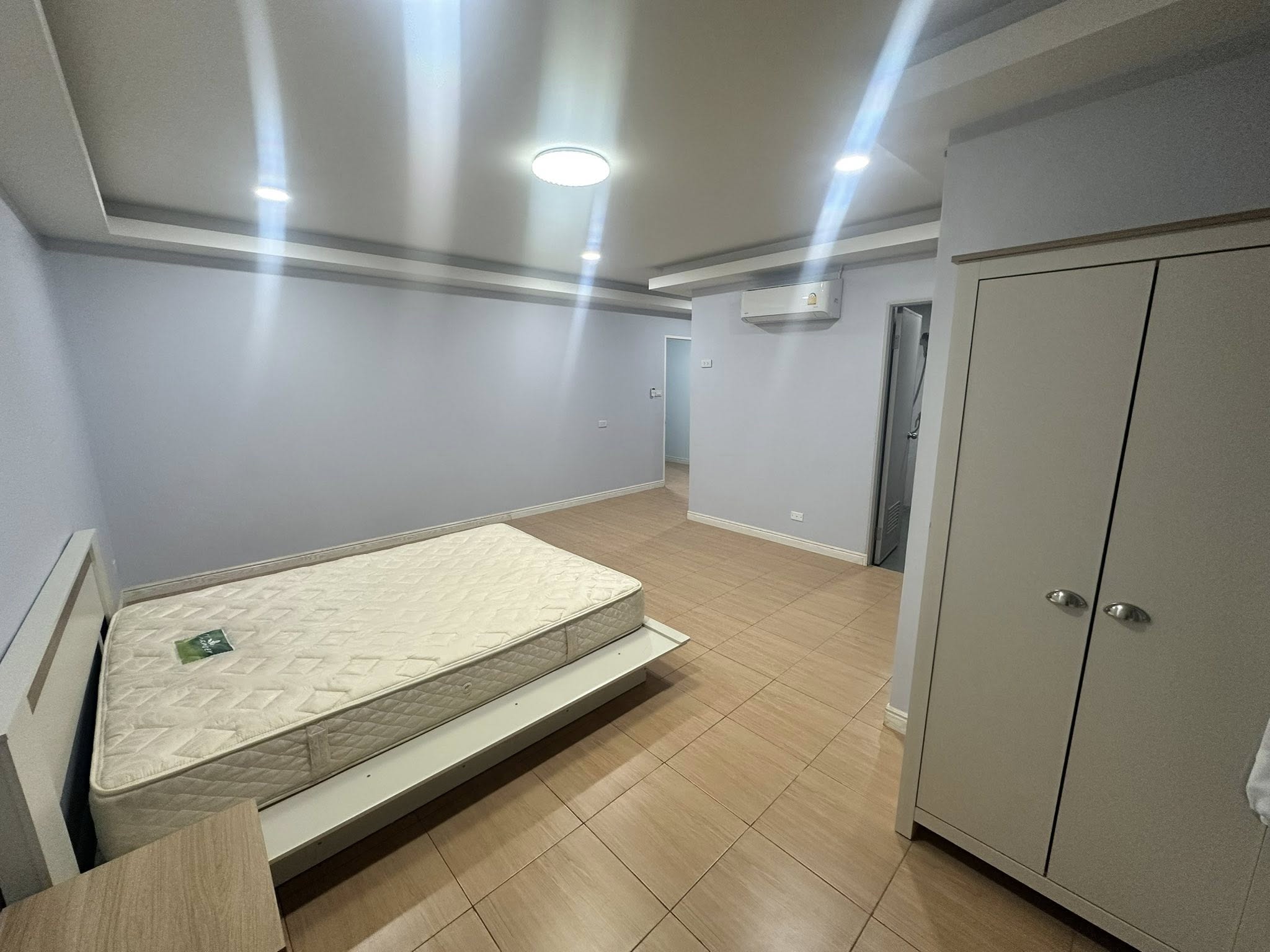 Home Office for rent in Wang Thonglang, Bangkok - Bedroom angle showing air conditioner, wardrobe and ensuite door.