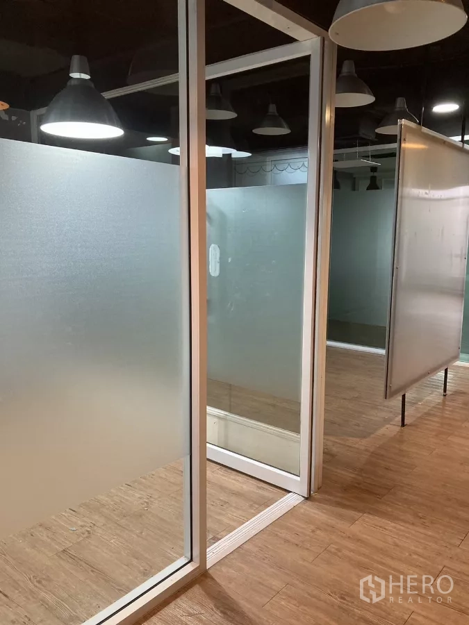 Office Space for rent in Watthana, Bangkok - Frosted-glass partitions with sliding door and wood floors under pendant lights in Watthana.