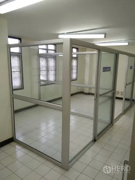 Townhouse for rent in Phra Khanong, Bangkok - Glass office cubicles inside a bright tiled room with strip lighting.
