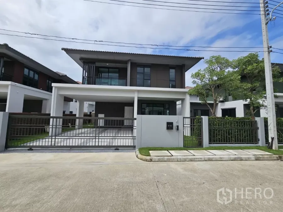Detached House for sale in Lam Luk Ka, Pathum Thani - Front exterior of a new two-storey detached house with gated driveway and double carport.