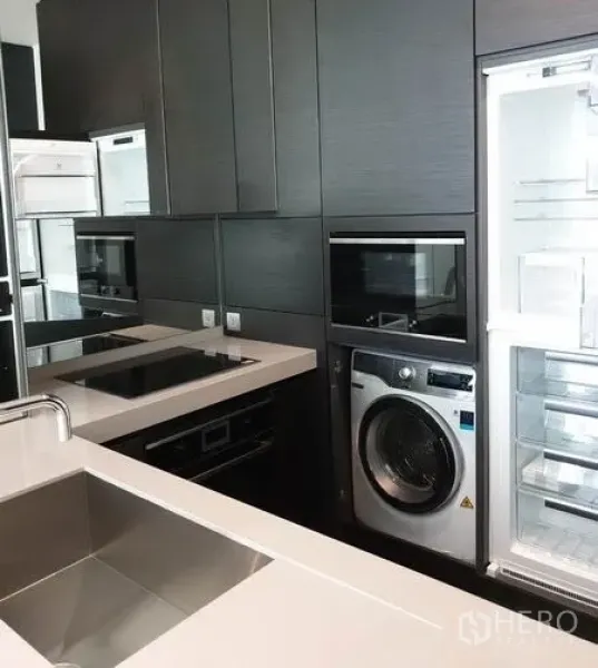 Condominium for rent in Pathum Wan, Bangkok - Contemporary kitchen with built-in oven, induction hob, stainless sink, refrigerator and washing machine.