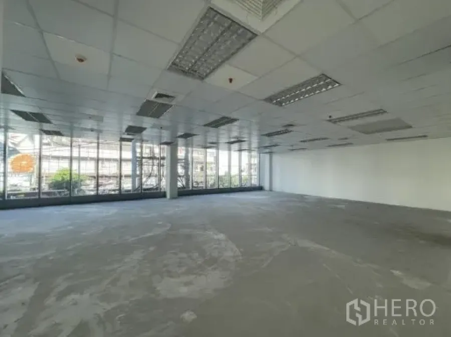 Office Space for rent in Khlong Toei, Bangkok - Open-plan office floor with floor-to-ceiling windows, grid ceiling, and concrete subfloor.