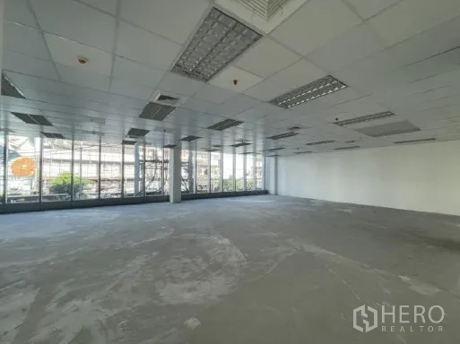 Office Space for rent in Khlong Toei, Bangkok - Open-plan office floor with floor-to-ceiling windows, grid ceiling, and concrete subfloor.