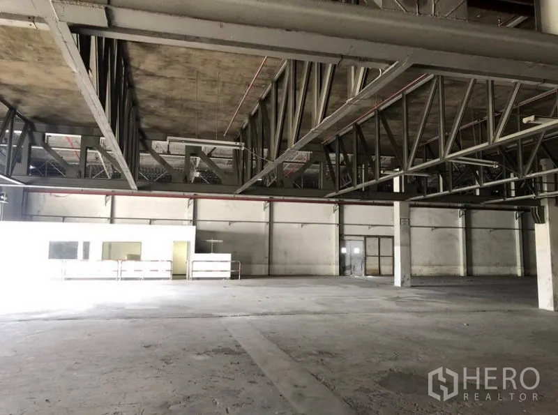 Warehouse for rent in Lam Luk Ka, Pathum Thani - Interior zone with steel mezzanine structure and attached office rooms.