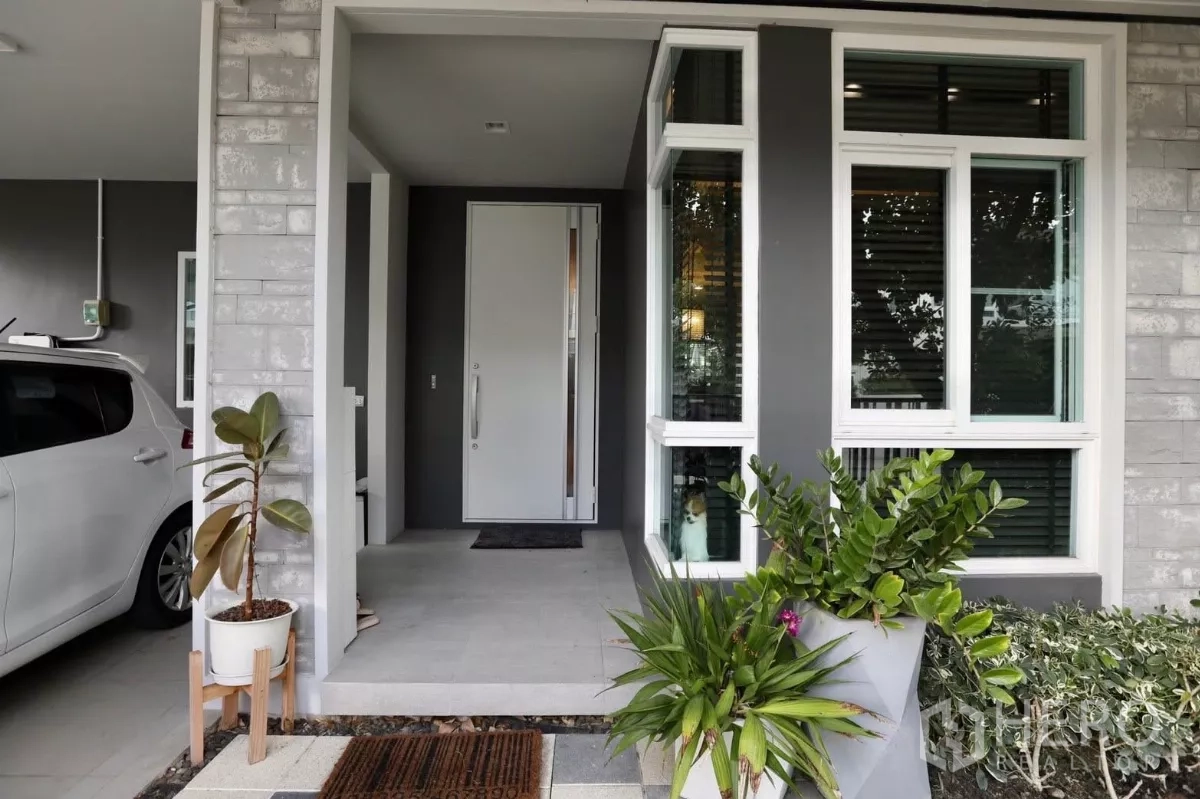 Detached House for rent in Samut Prakan - Side garden with shaded seating area and checker pathway.