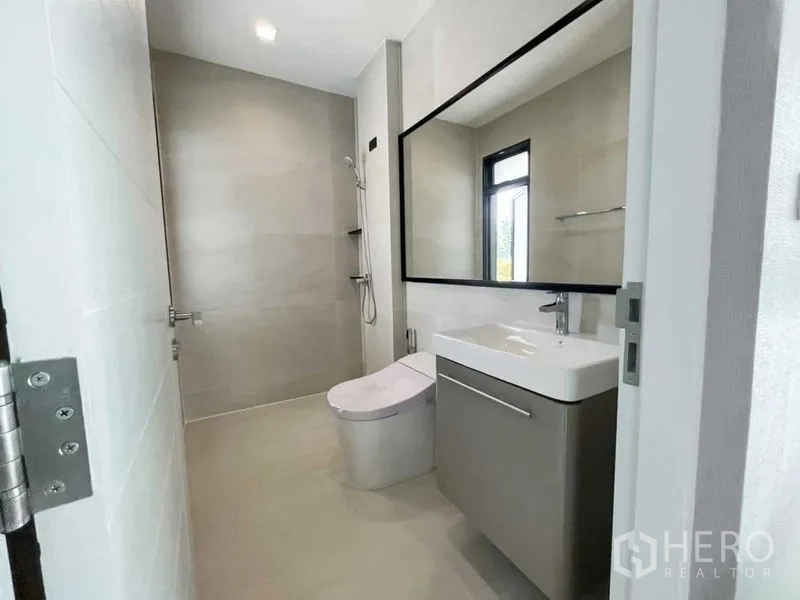 Detached House for sale in Mueang Nonthaburi, Nonthaburi - Minimalist bathroom featuring walk-in shower, modern vanity, and window.