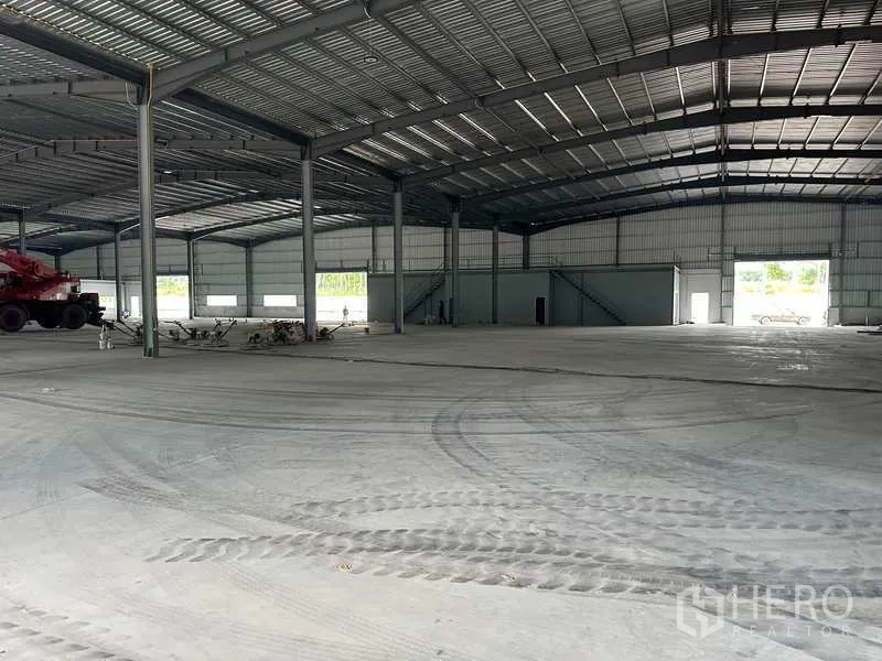 Factory for rent in Rayong - High-clear warehouse interior with wide bays, mezzanine stairs and drive-through access.