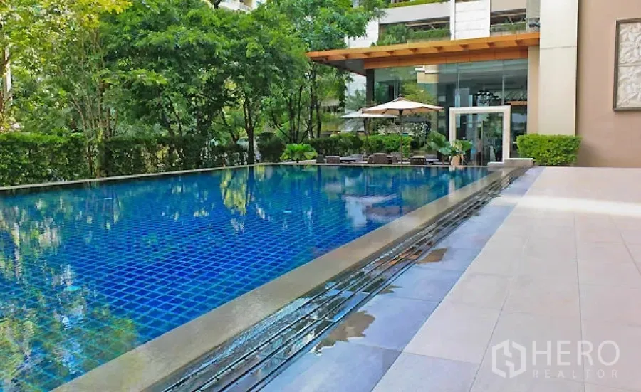Condominium for rent in Pathum Wan, Bangkok - Condominium outdoor swimming pool with blue tiles, sundeck and greenery in Pathum Wan, Bangkok.