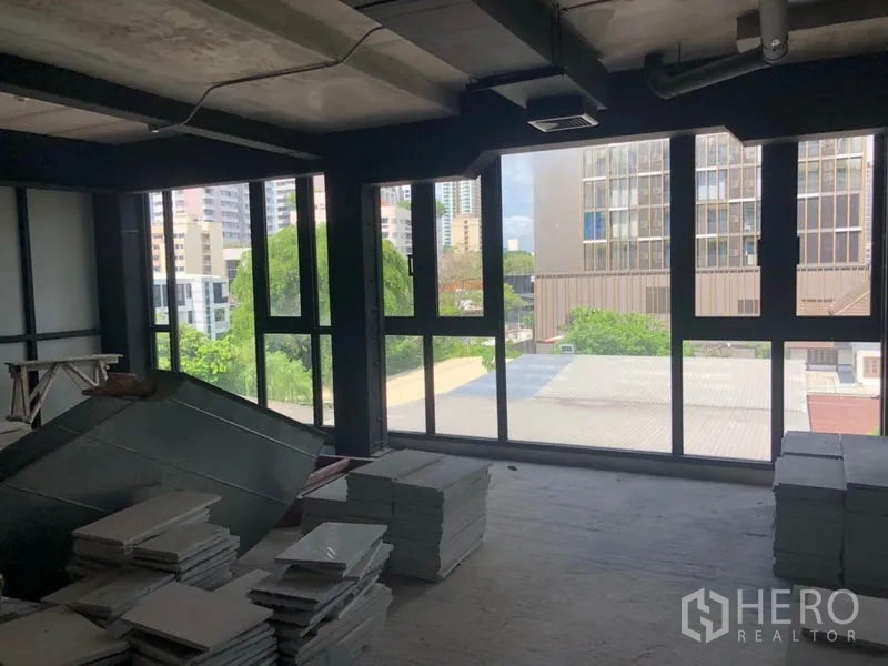 Retail Space for rent in Khlong Toei, Bangkok - Unfinished retail floor with stacked tiles and large windows looking over the city.