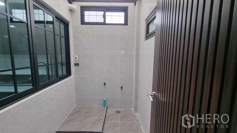 Townhouse for rent in Khlong Toei, Bangkok - Tiled bathroom or shower area with ventilation windows and floor drain.