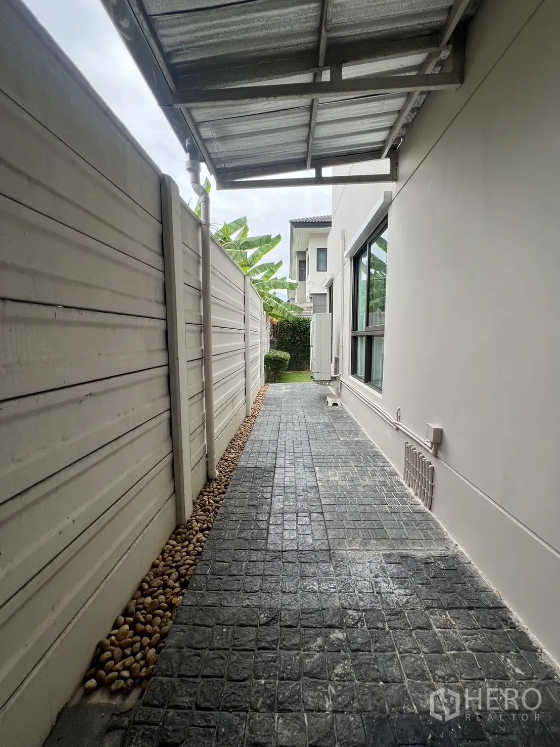 Detached House for rent or sale in Prawet, Bangkok - Covered side walkway with stamped concrete path and pebble drain.