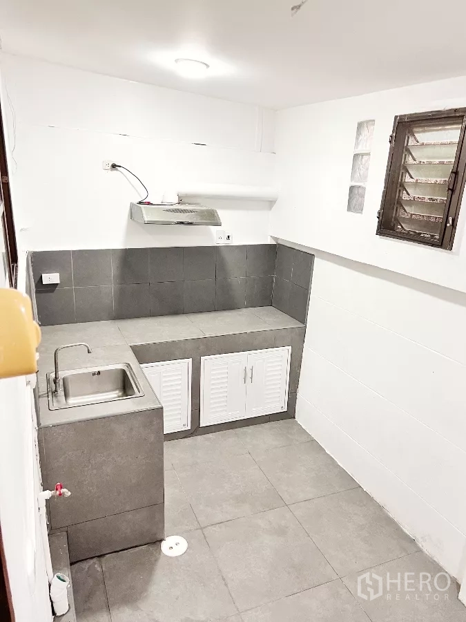 Townhouse for rent or sale in Phra Khanong, Bangkok - Separate Thai kitchen with tiled counters, sink and cooker hood.