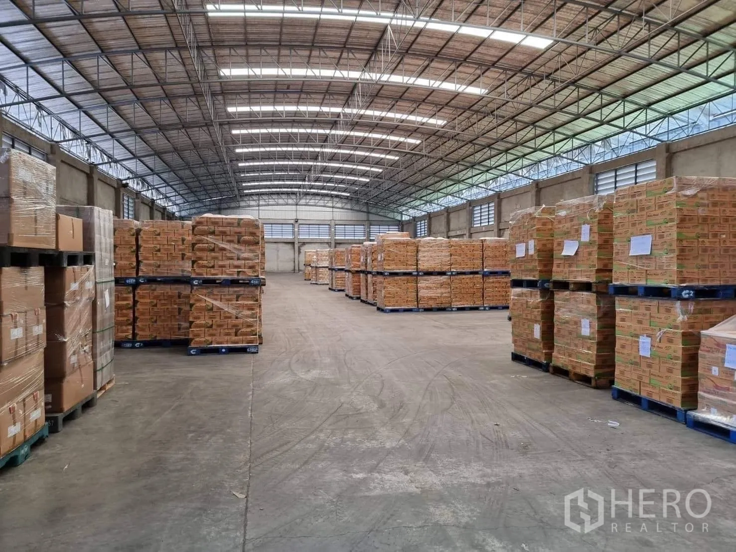 Factory for rent or sale in Pathum Thani - Neatly stacked pallets under an arched roof with bright skylights.