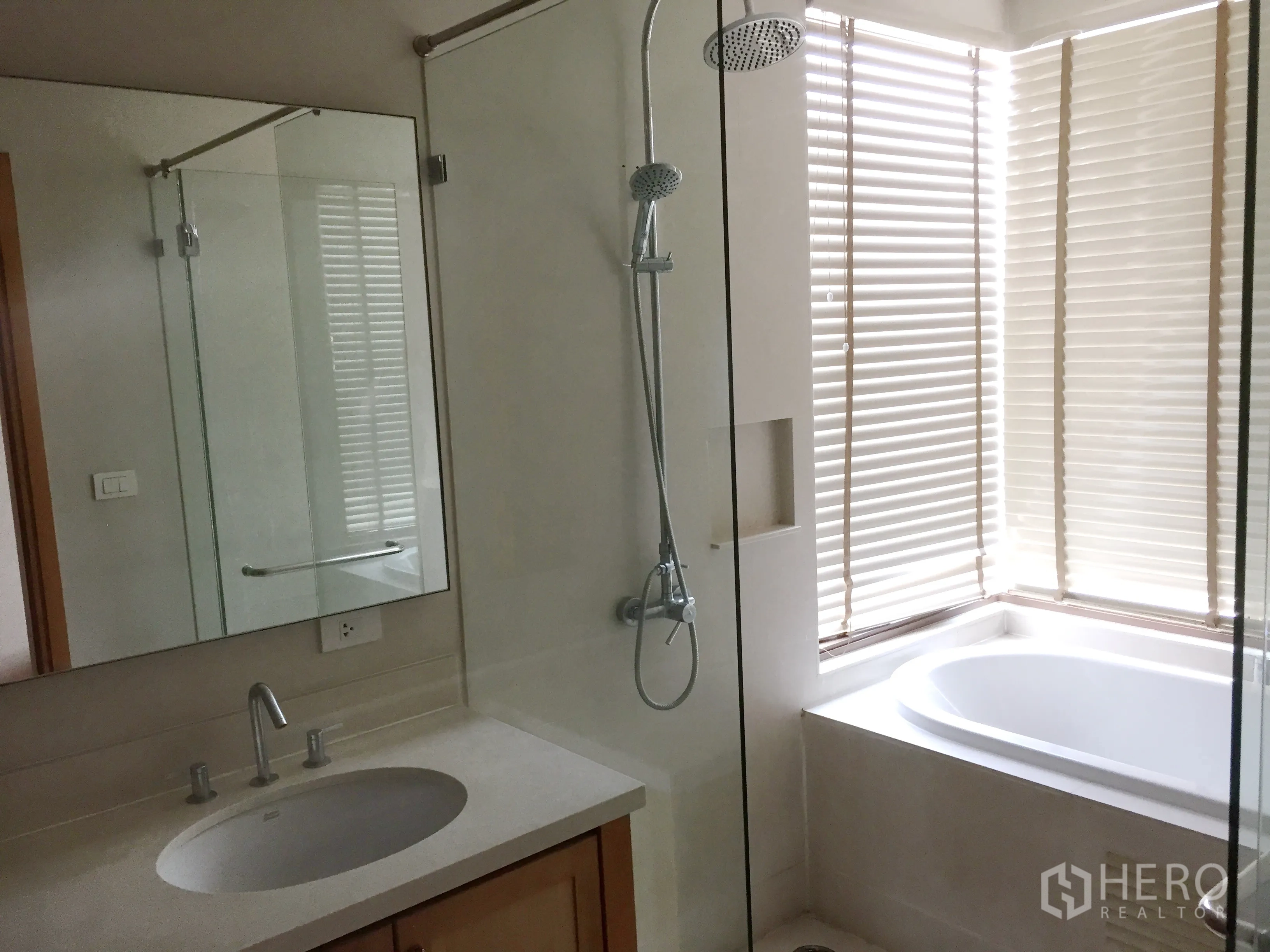 Condominium for rent in Khlong Toei, Bangkok - Modern bathroom featuring glass-enclosed shower, separate bathtub, large mirror, and vanity.