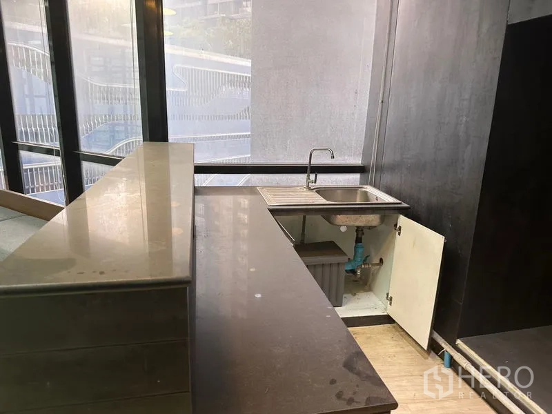 Office Space for rent in Din Daeng, Bangkok - Small pantry with stone countertop, sink and under-cabinet storage by window.