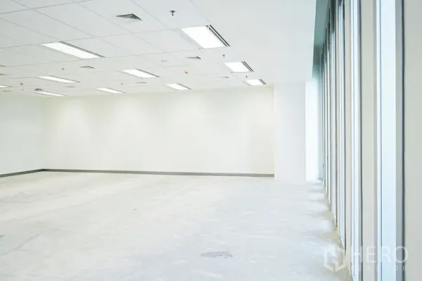 Office Space for rent in Bang Na, Bangkok - Open office zone beside a wall of tall windows providing abundant natural light and suspended ceiling fixtures.