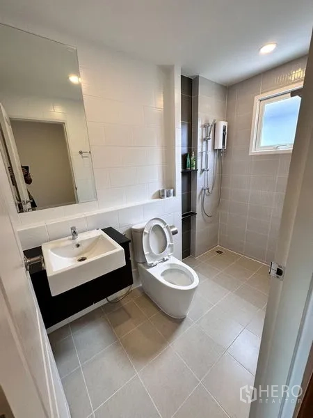 Detached House for sale in Prawet, Bangkok - Tiled bathroom with shower area, toilet, sink and small window.