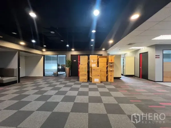 Office Space for rent in Huai Khwang, Bangkok - Spacious open-plan office with checkered carpet and stacked boxes under spotlights.