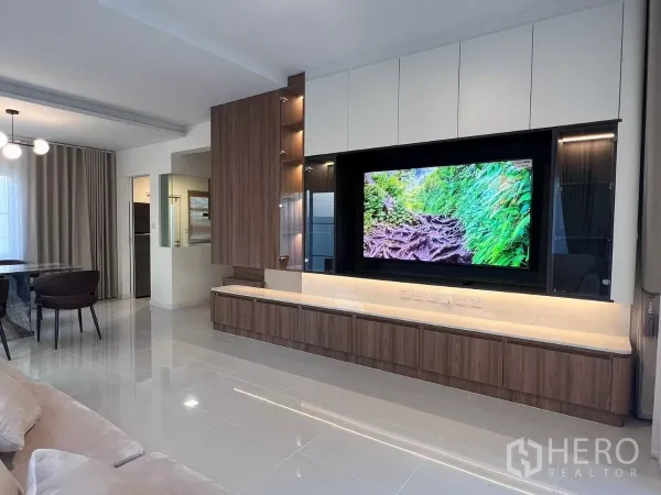Detached House for rent in Bang Phli, Samut Prakan - Open-plan lounge with custom wood TV cabinet and built-ins, with views to the dining area and kitchen.