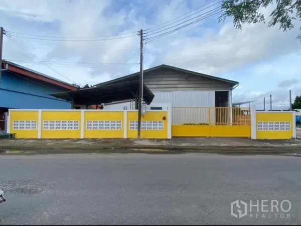 Warehouse for rent in Mueang Rayong, Rayong - Street view of a gated warehouse compound with a yellow perimeter wall and sliding gate in Mueang Rayong.
