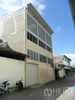 Factory for rent in Thung Khru, Bangkok - Side view of the factory with large ventilation louvers and a roller shutter door.